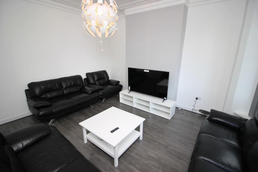 A modern living room with sleek black leather s...