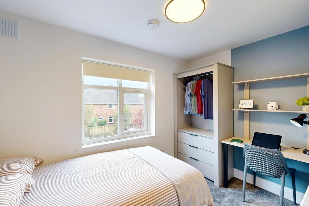 A bright and tidy student bedroom featuring a c...