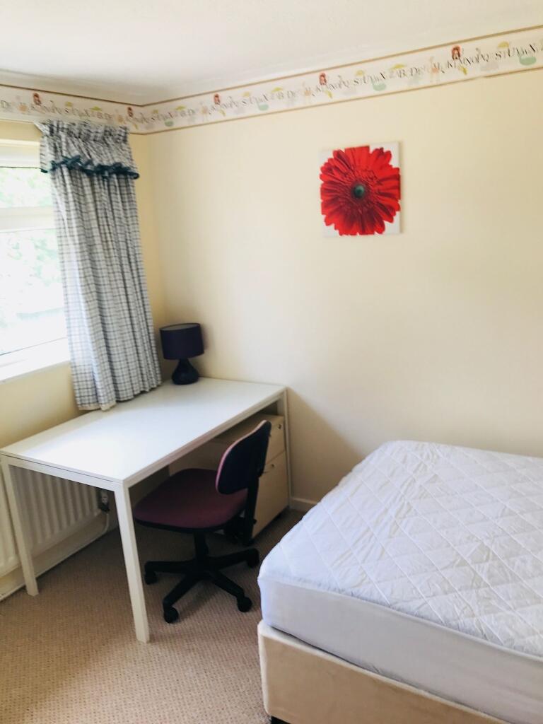 A cozy bedroom featuring a single bed, a desk w...