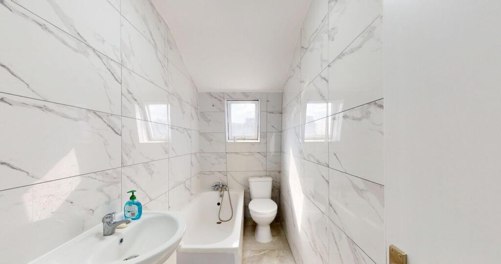 A sleek, modern bathroom featuring a white bath...