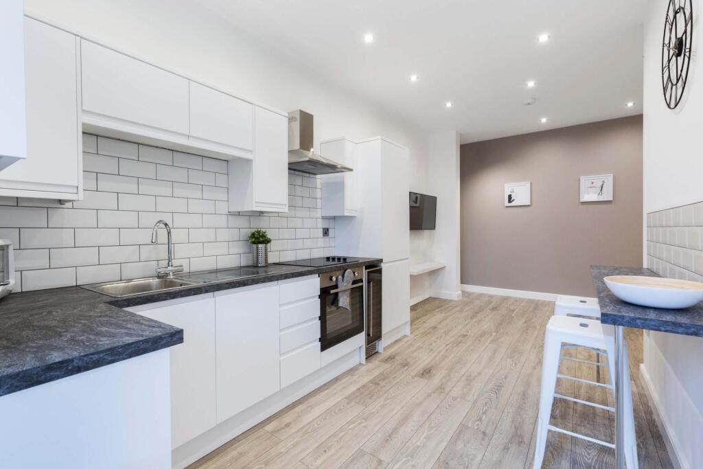 Bright modern kitchen with white cabinetry, sub...