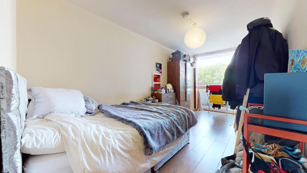 A bright double bedroom featuring a large windo...