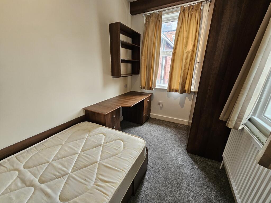 A cozy single bedroom featuring a comfortable b...