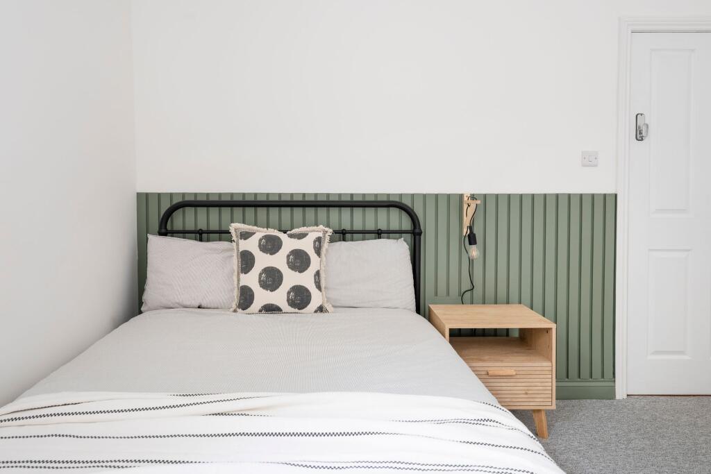 Bright, neatly styled double bedroom with a bla...
