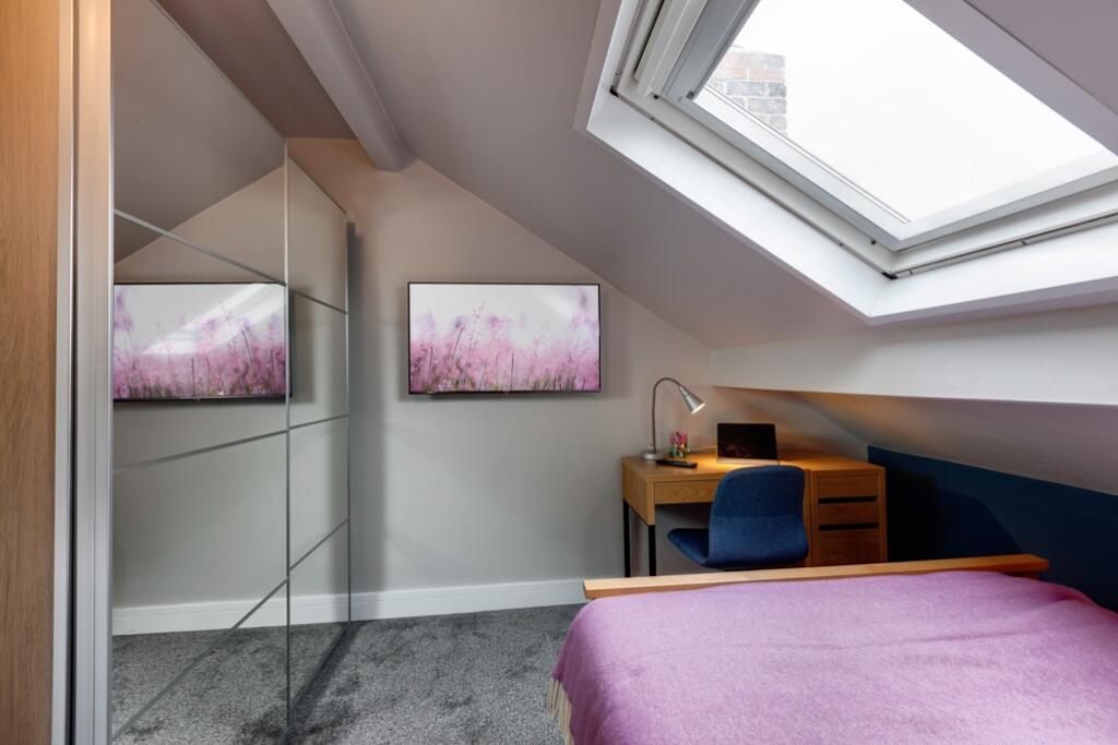 A cozy and well-lit bedroom with a sloped ceili...