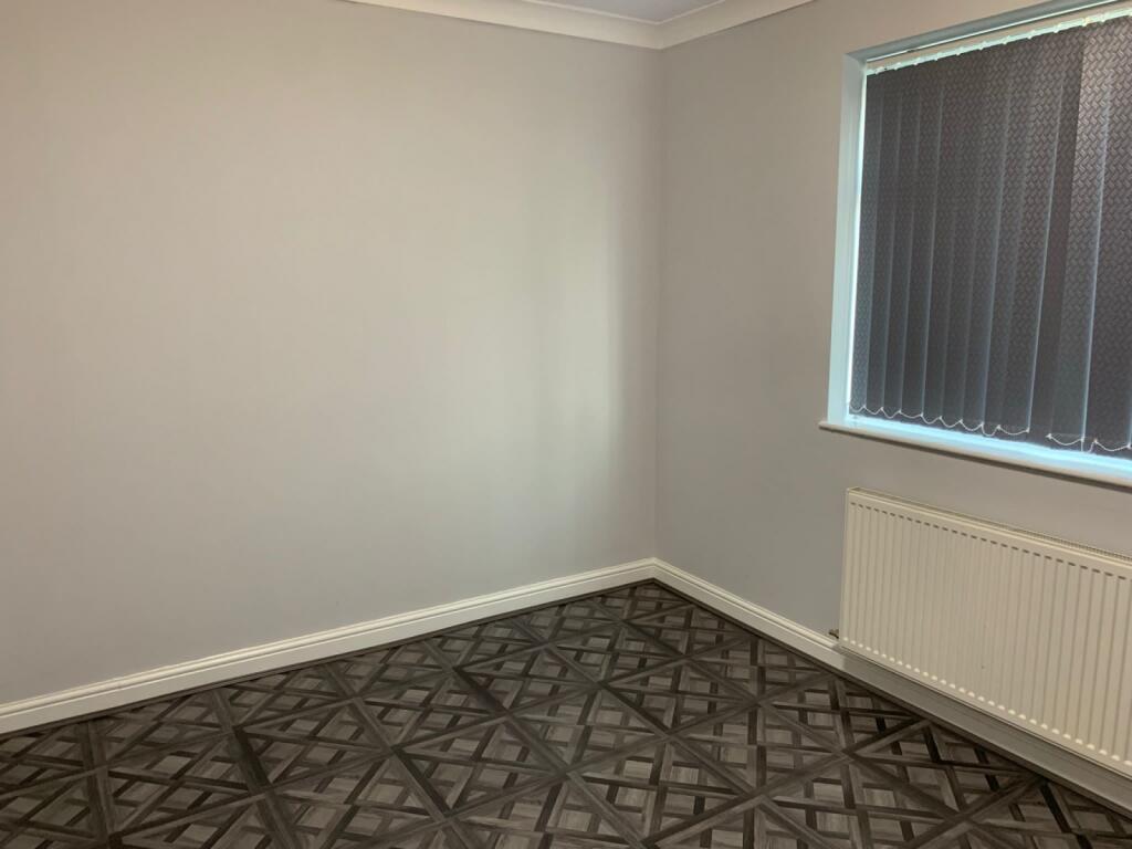 A clean, neutral single bedroom featuring a pat...