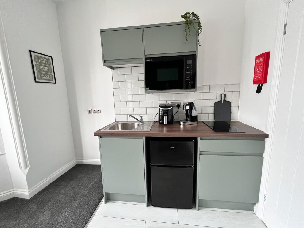 Modern kitchenette featuring sleek cabinetry, e...