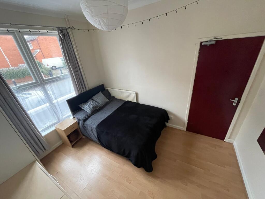A cozy bedroom featuring a double bed with dark...