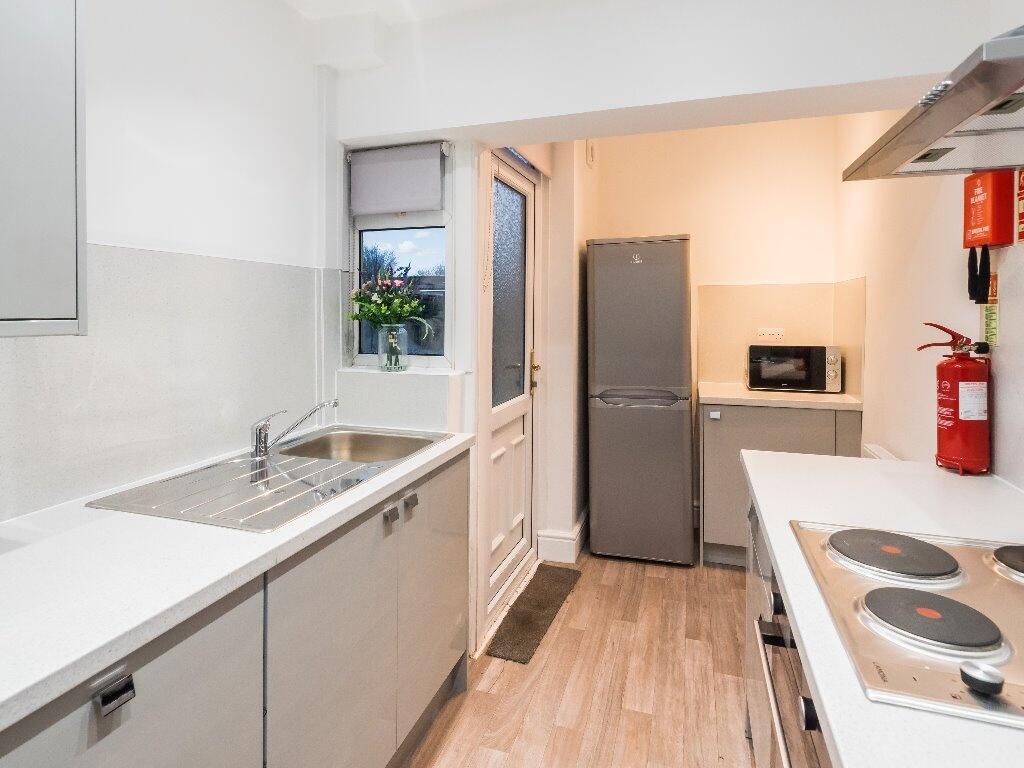 A bright and modern kitchen featuring white cou...