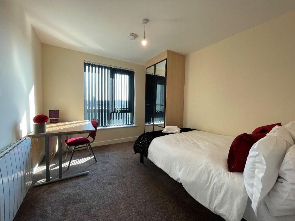 A bright, tidy single bedroom featuring a comfo...