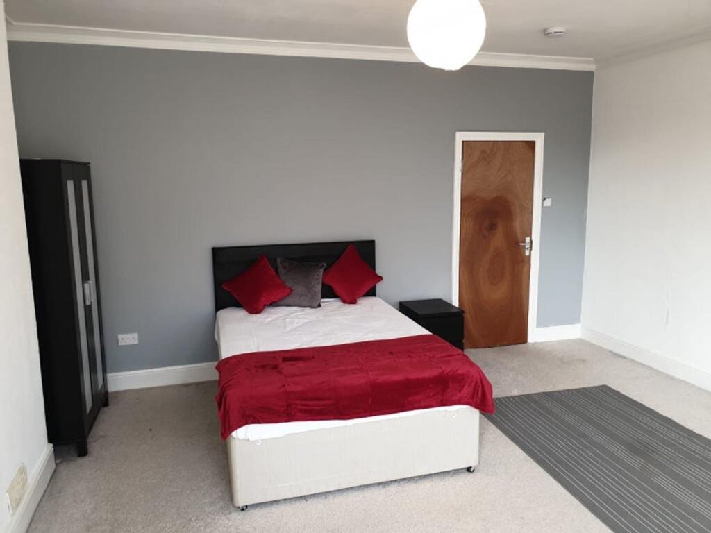 A tidy double bedroom featuring a bed with red ...