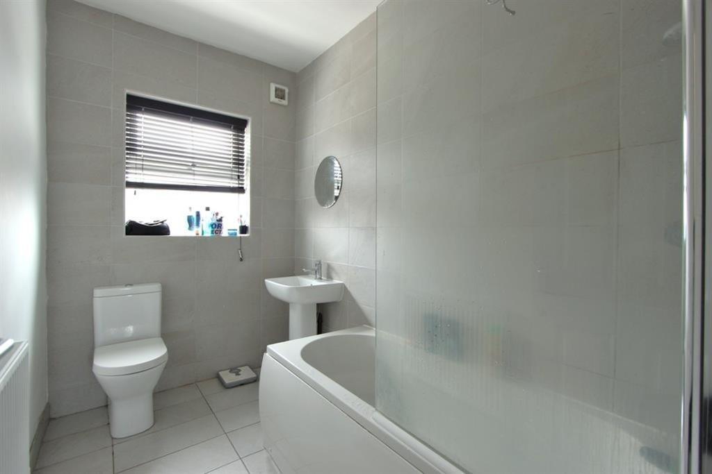 A bright, modern bathroom featuring a clean whi...