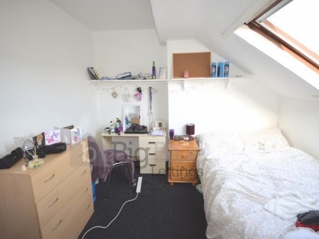 Bright and cozy attic bedroom featuring slanted...