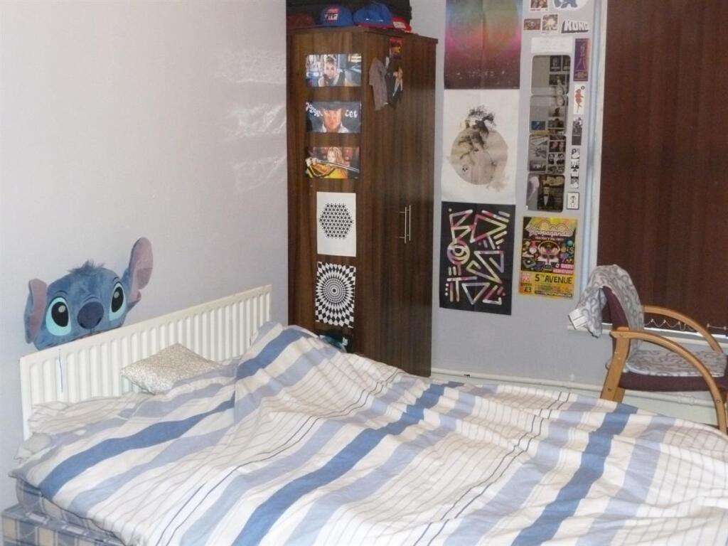 Cozy bedroom with a striped duvet, radiator, wa...