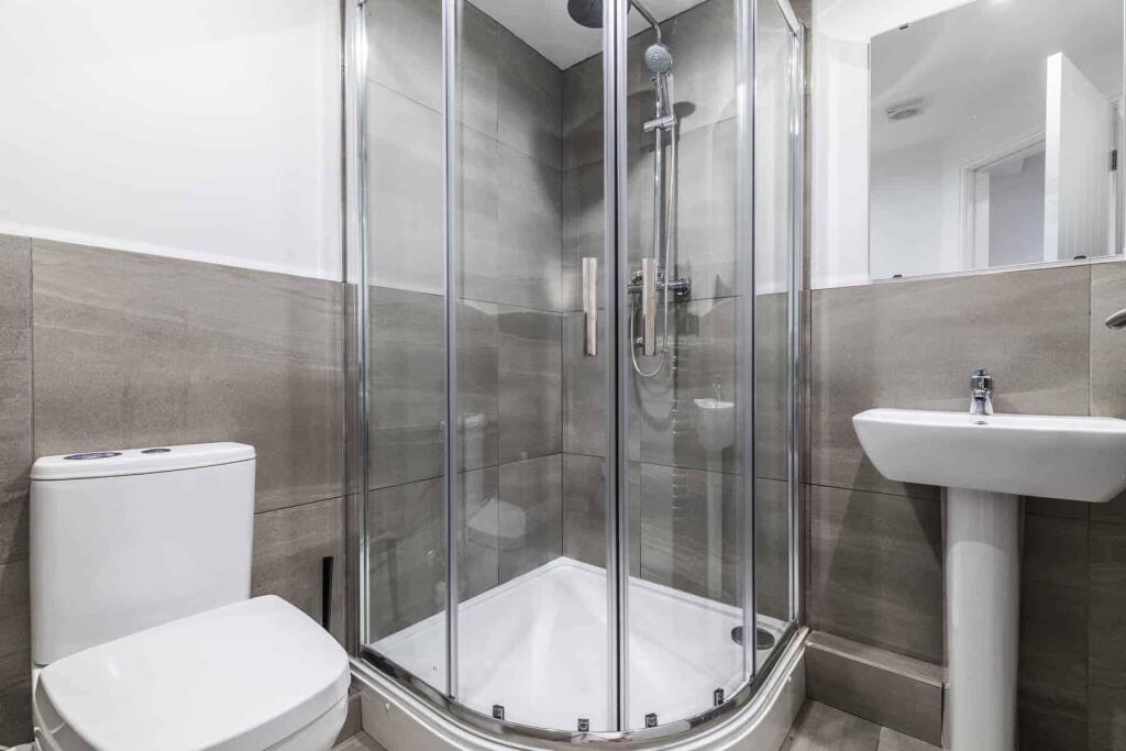 Modern bathroom with a corner glass shower encl...