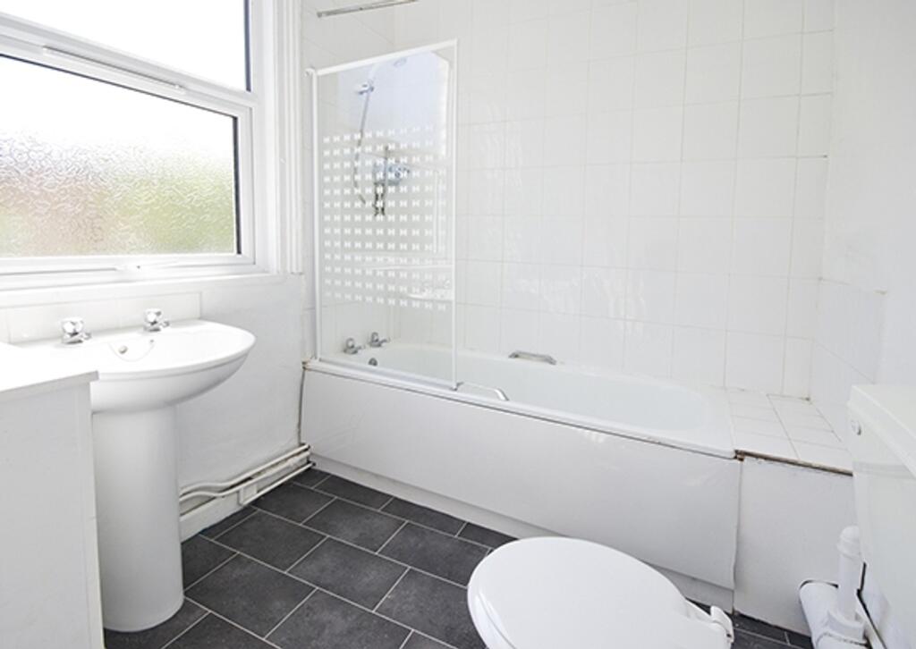 A bright and tidy bathroom featuring a bathtub ...