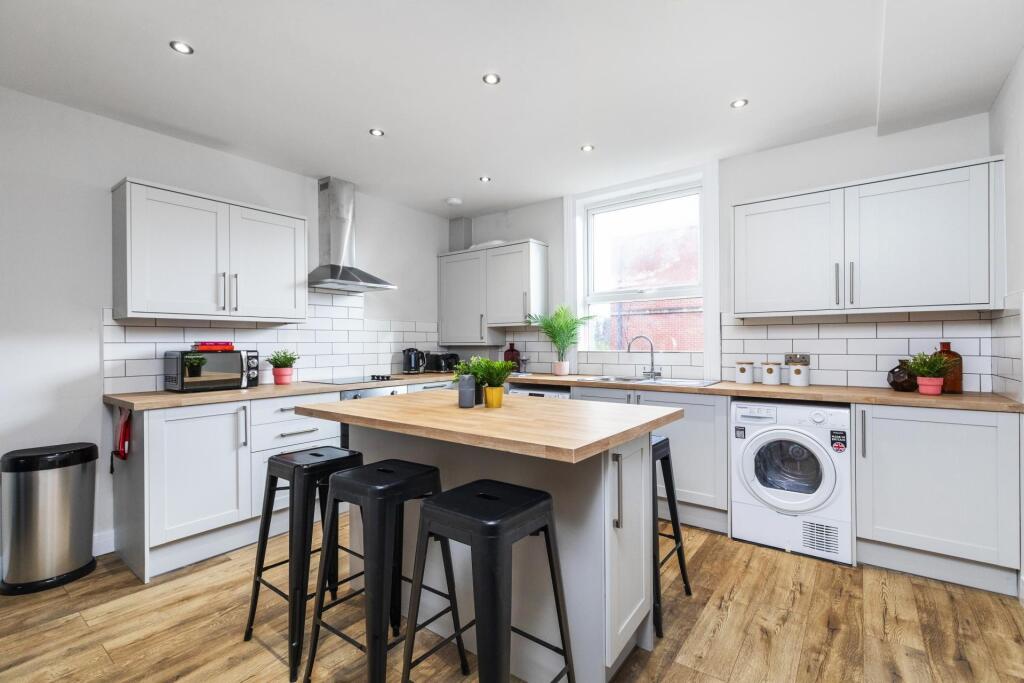Bright modern kitchen with white cabinetry, a c...