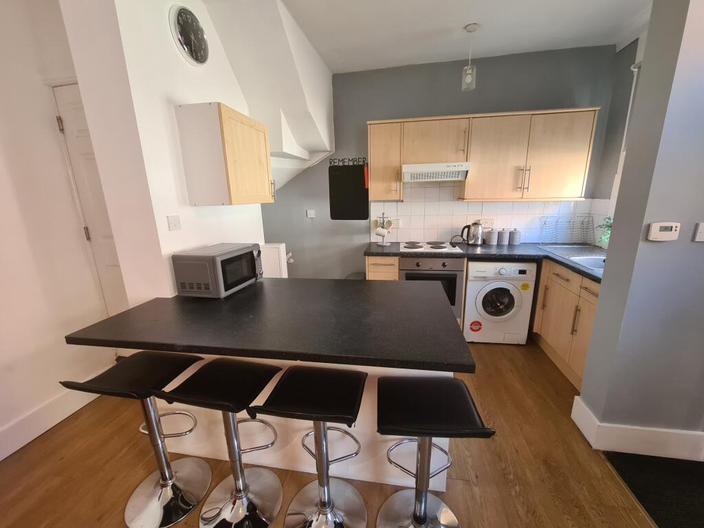 A modern kitchen featuring a breakfast bar with...