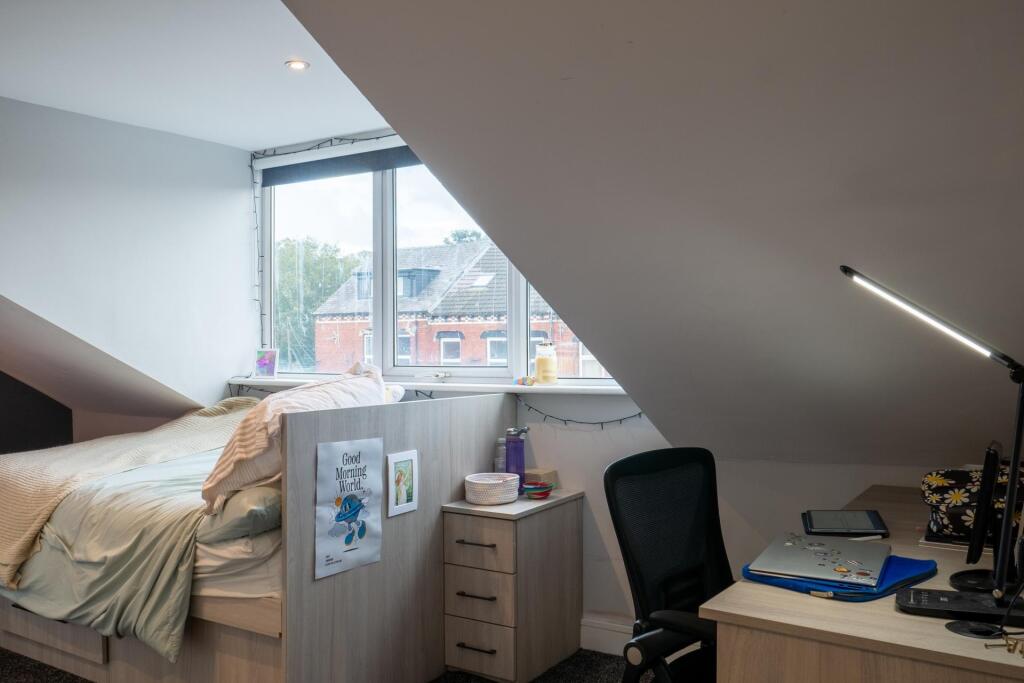 A bright and welcoming bedroom featuring a comf...