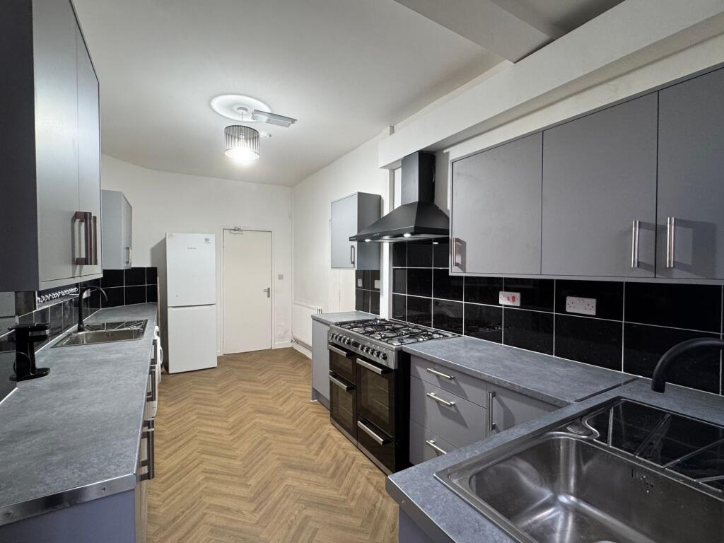 A modern galley kitchen featuring sleek grey ca...