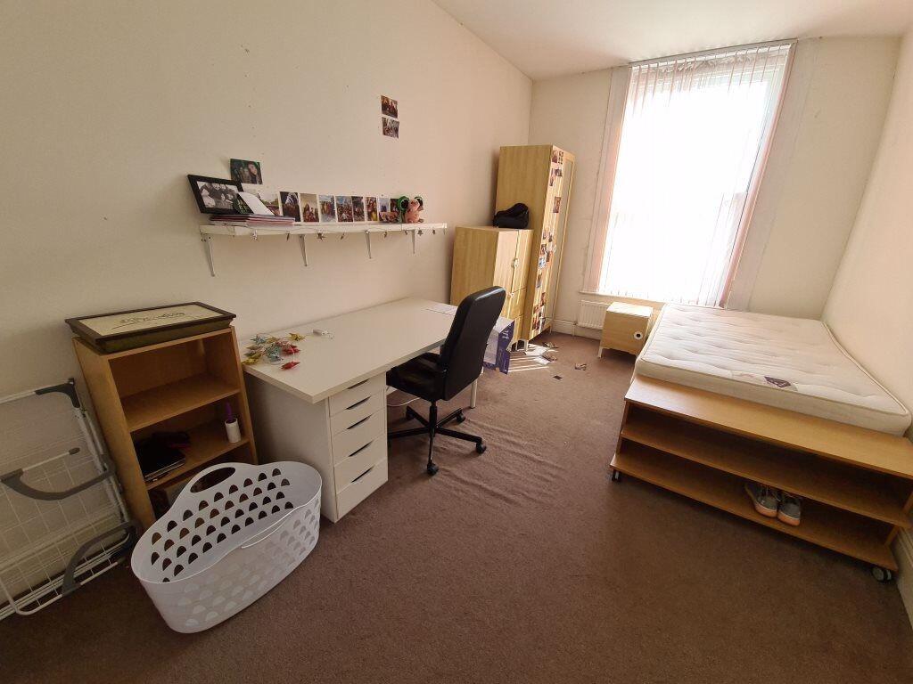 A simple, well-lit student bedroom featuring a ...