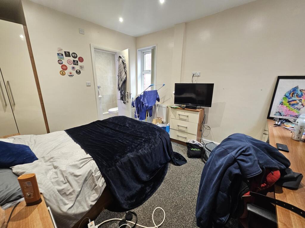 A cozy bedroom with a bed, small workspace, and...