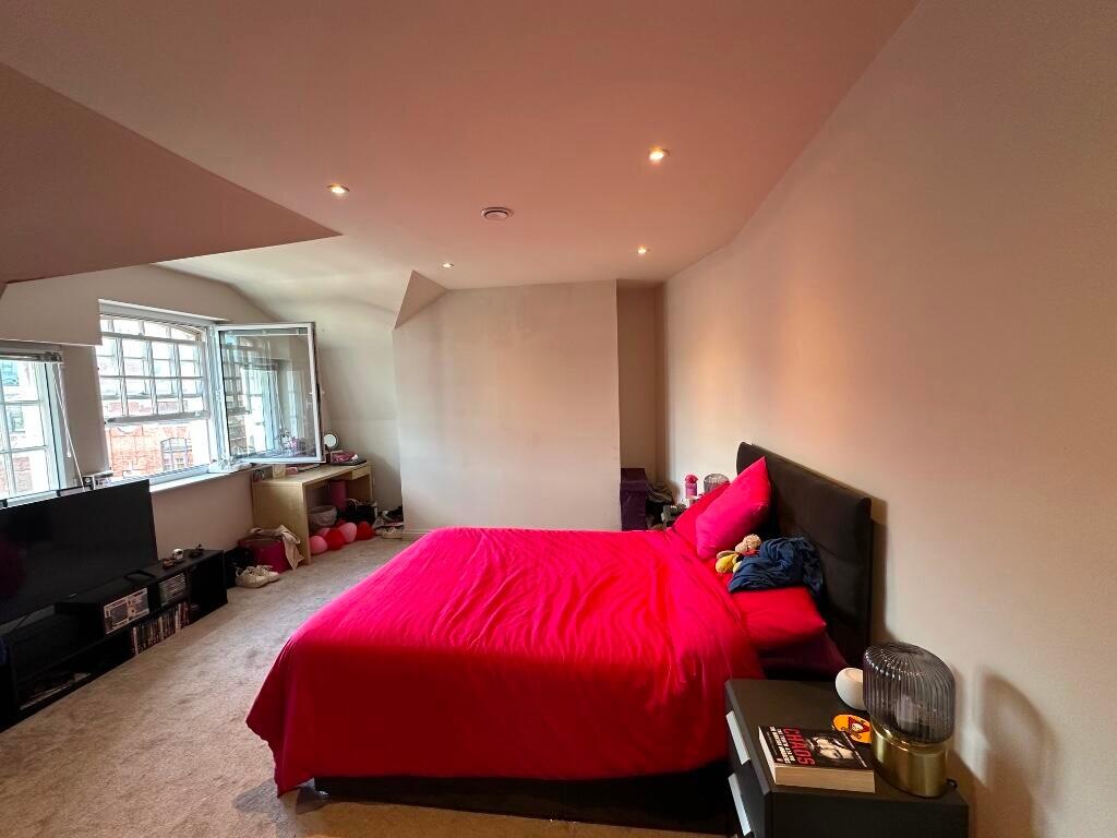 A spacious master bedroom featuring a comfortab...