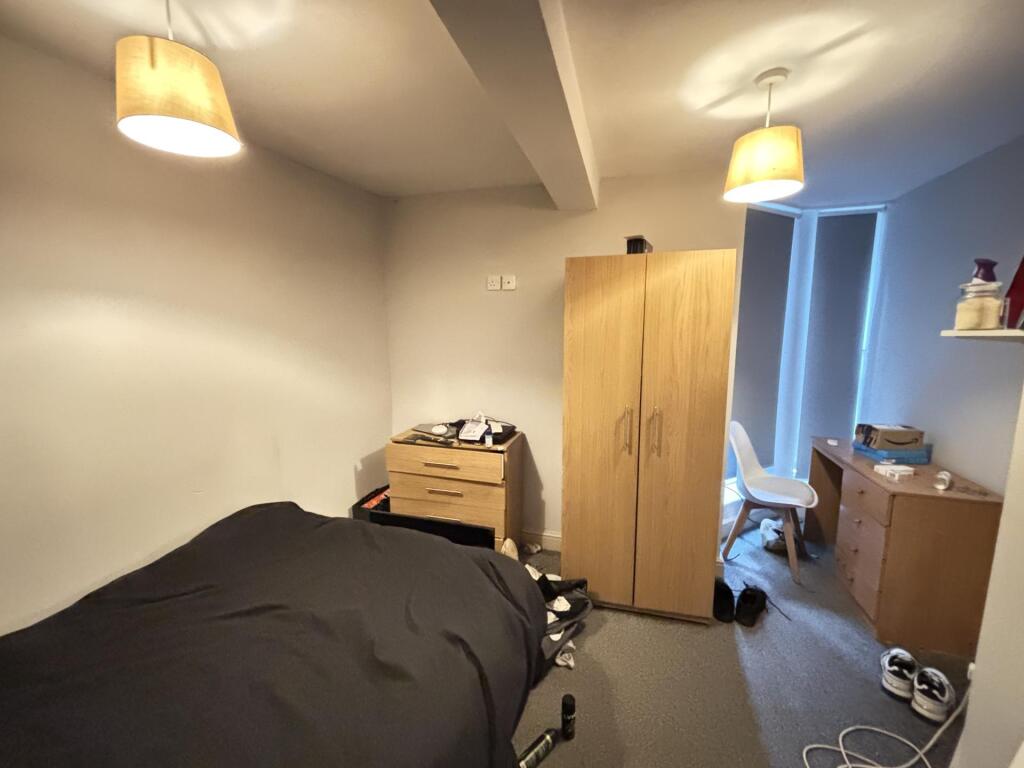 A cozy bedroom featuring a large bed, a small w...