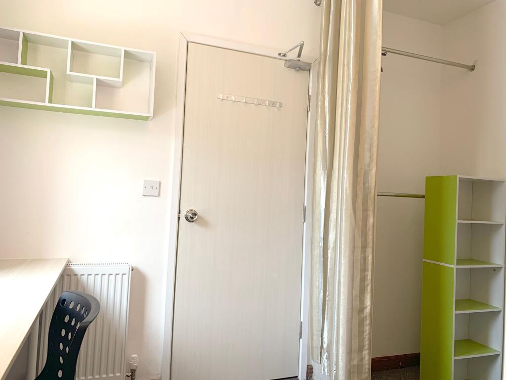 A bright and tidy single bedroom featuring mode...