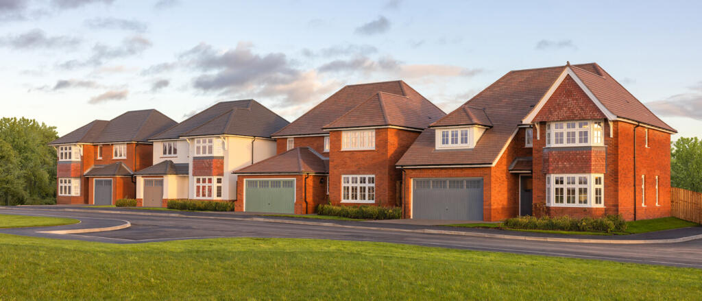 A row of modern red-brick and white houses with pitched roofs, set against a partly cloudy sky and s