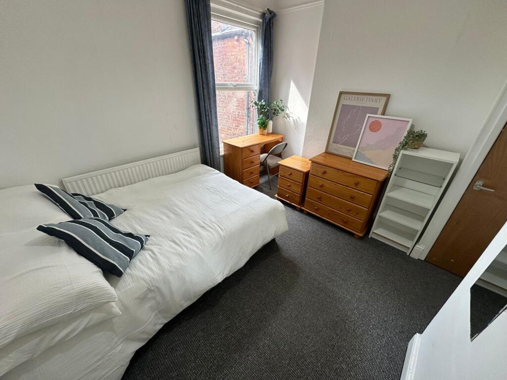 A well-maintained double bedroom with a comfort...