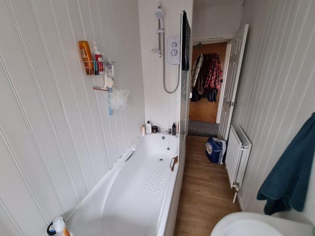 Bright, clean bathroom with a white bathtub, wa...