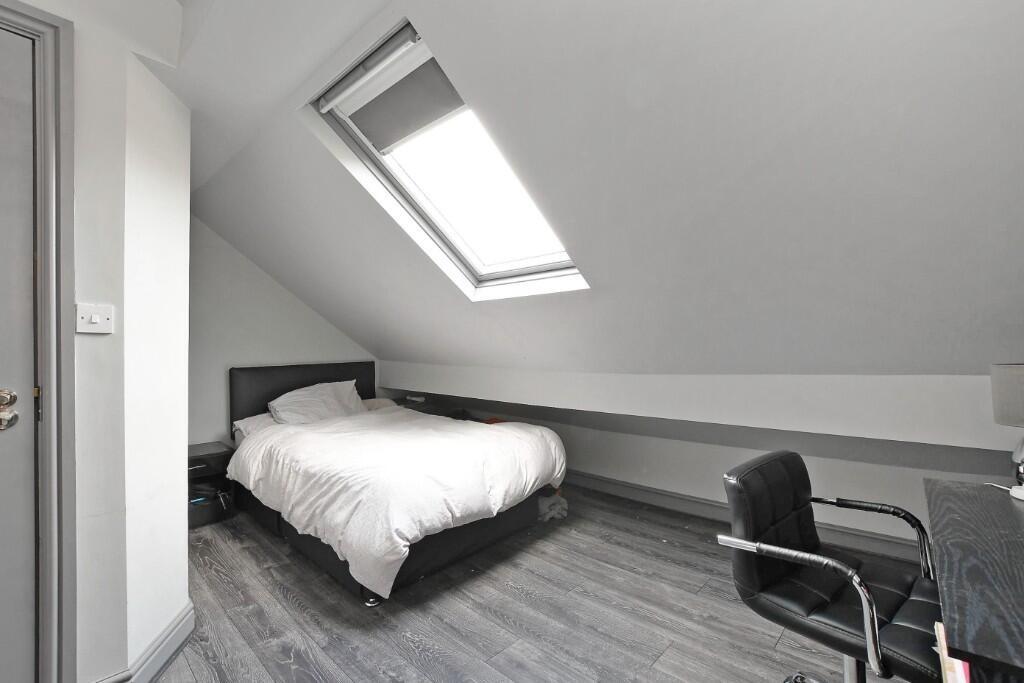 A neat and minimalist attic bedroom featuring a...