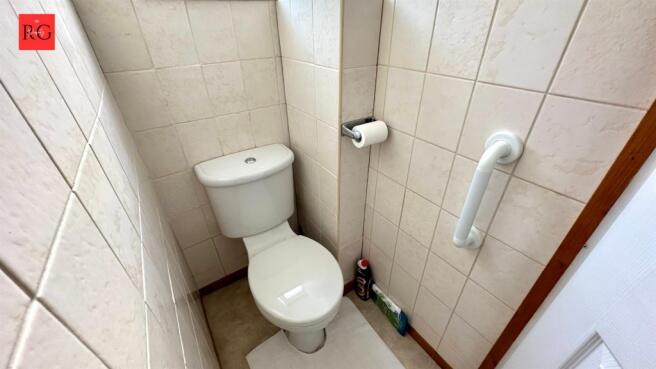 Compact and clean single toilet with tiled wall...