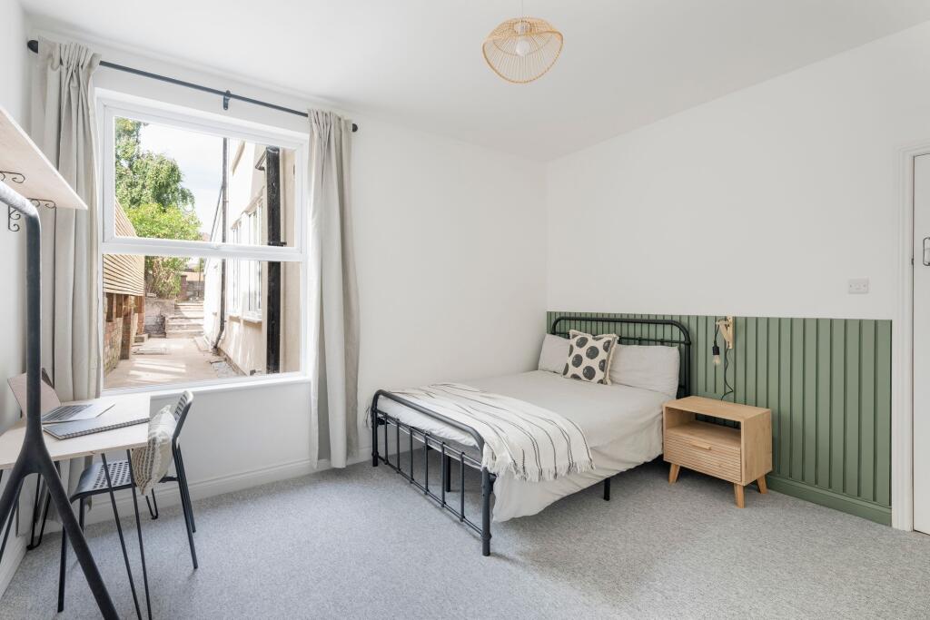 Bright, neatly styled bedroom with a metal doub...