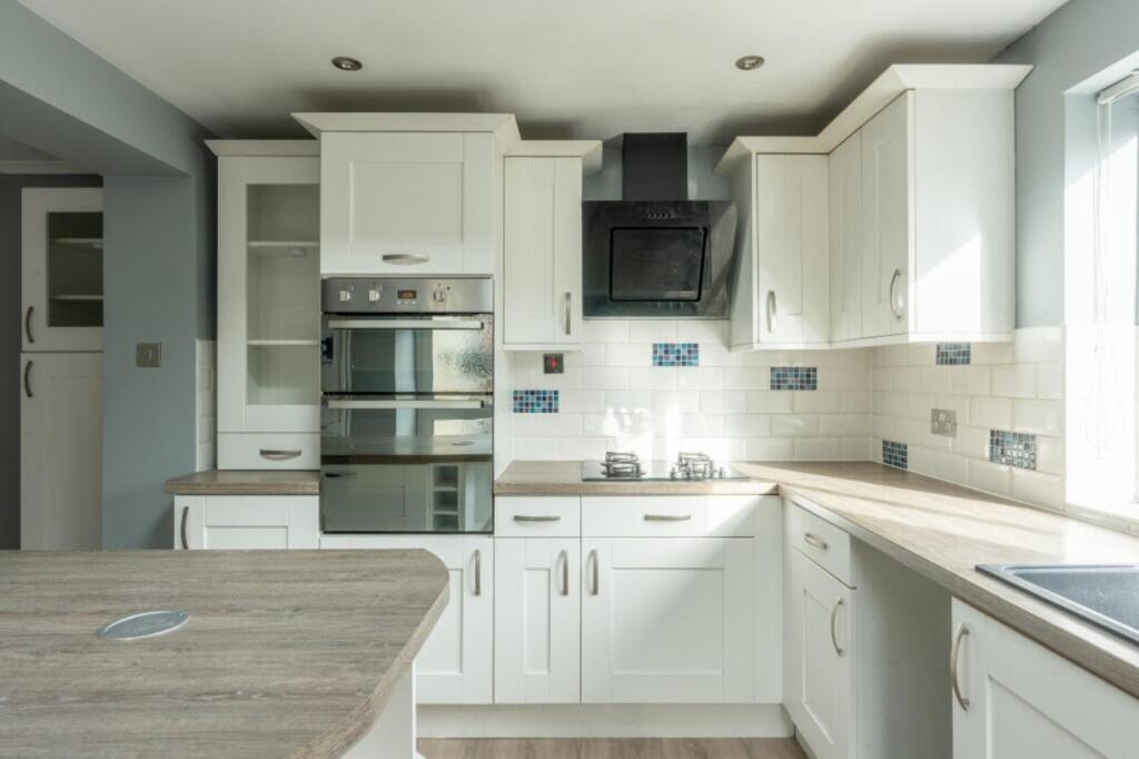 A bright and modern kitchen featuring ample sto...