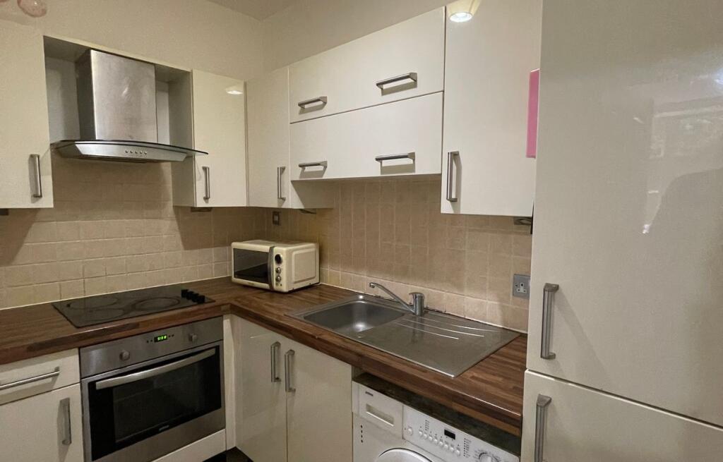 Modern kitchen featuring white cabinets with a ...