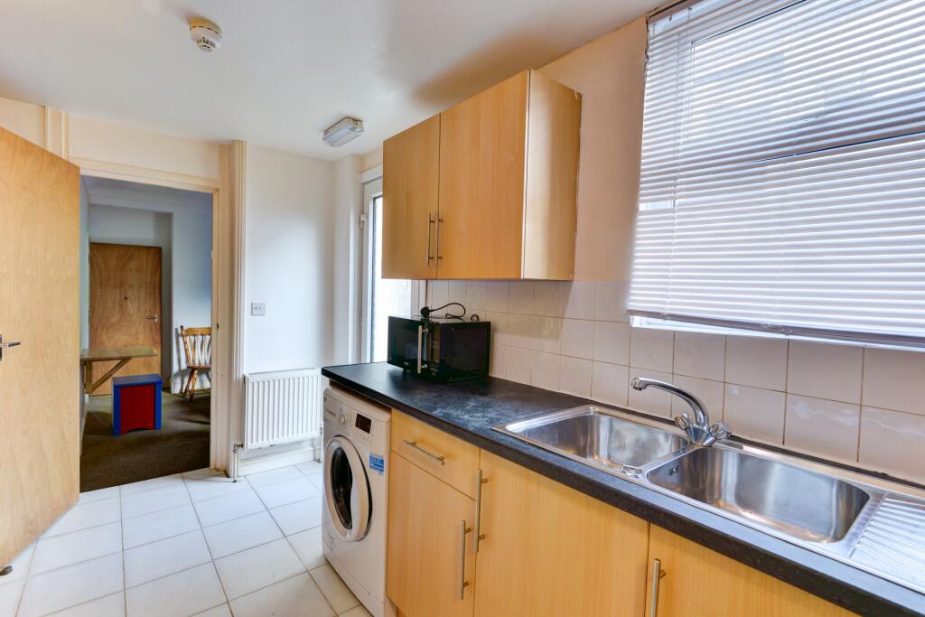 Bright and tidy kitchen featuring light wood ca...