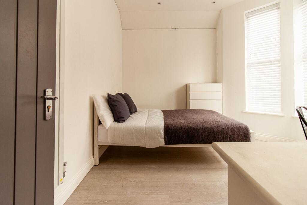 Bright, neatly styled bedroom with a comfortabl...