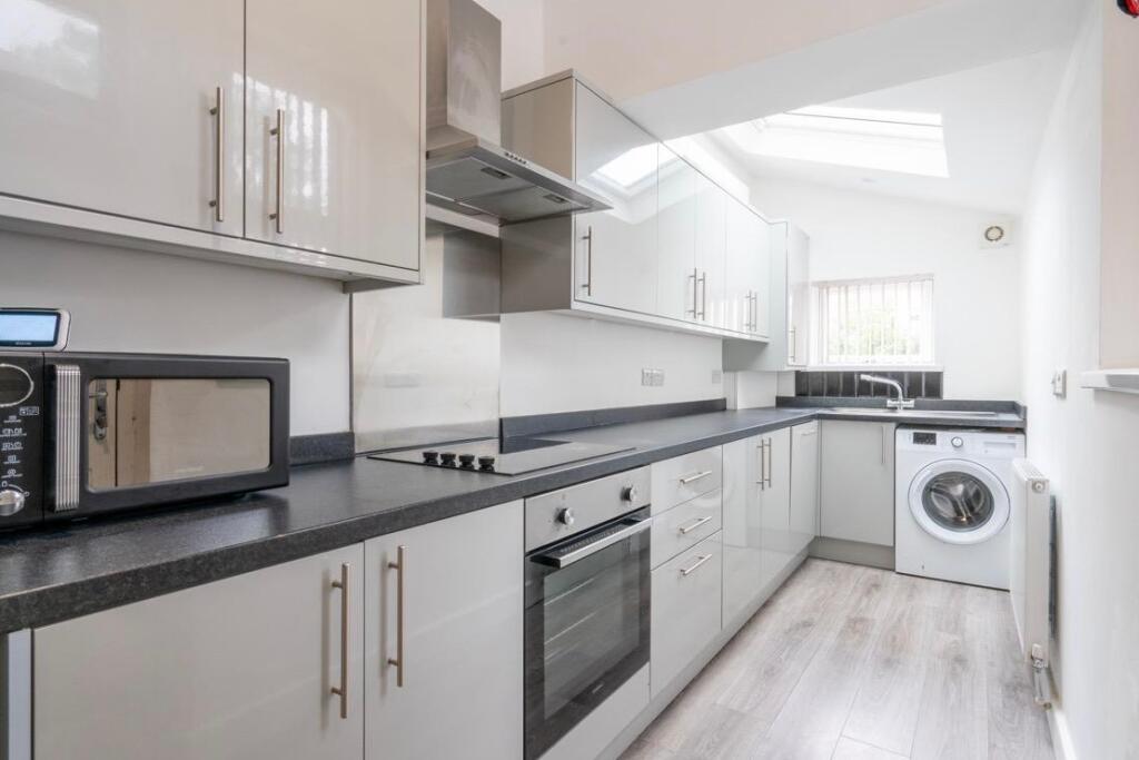 Modern galley kitchen with sleek white cabinetr...