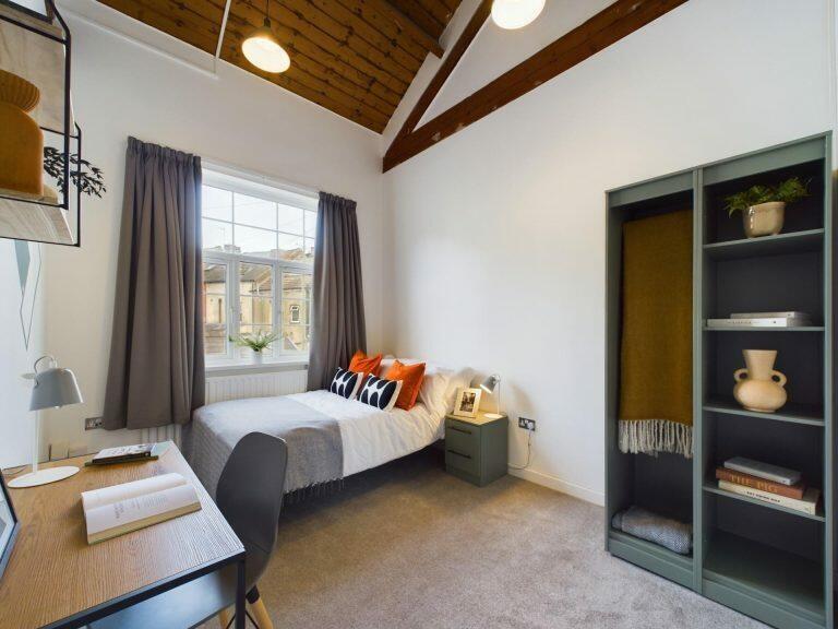 A bright and cozy single bedroom featuring a co...