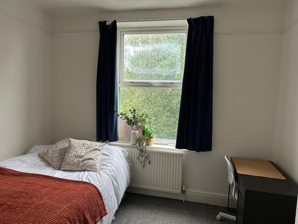 A cozy single bedroom featuring a single bed wi...