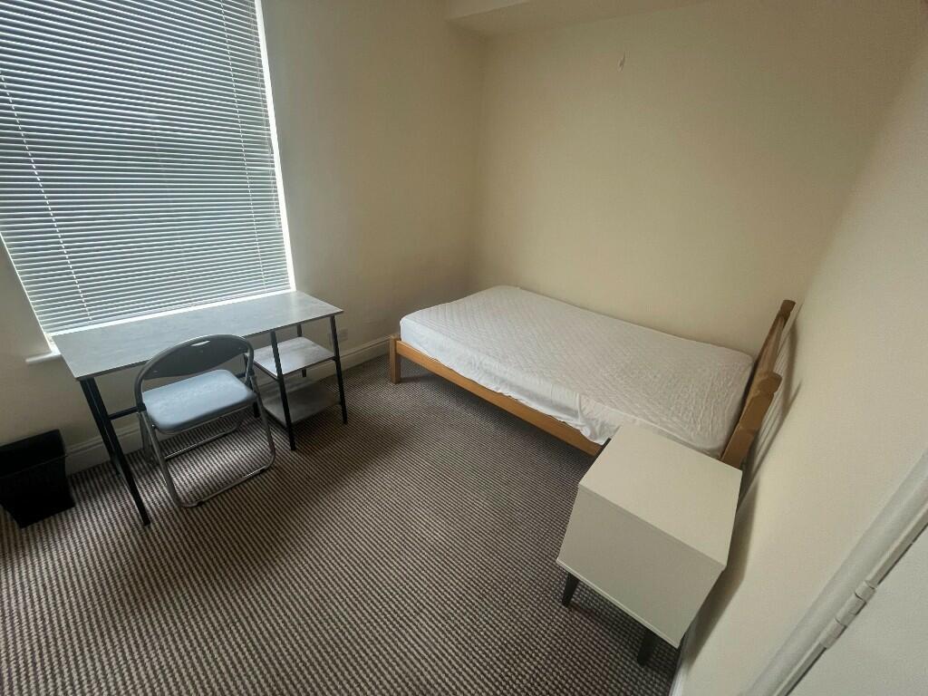 A simple and tidy single bedroom with a bed, de...