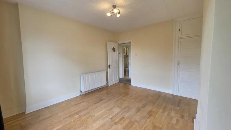 Bright and spacious bedroom with warm wooden fl...