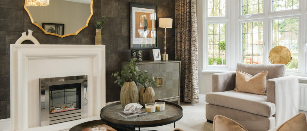 A cosy living room with a white fireplace, beige armchair, decorative vases, framed artwork, and lar