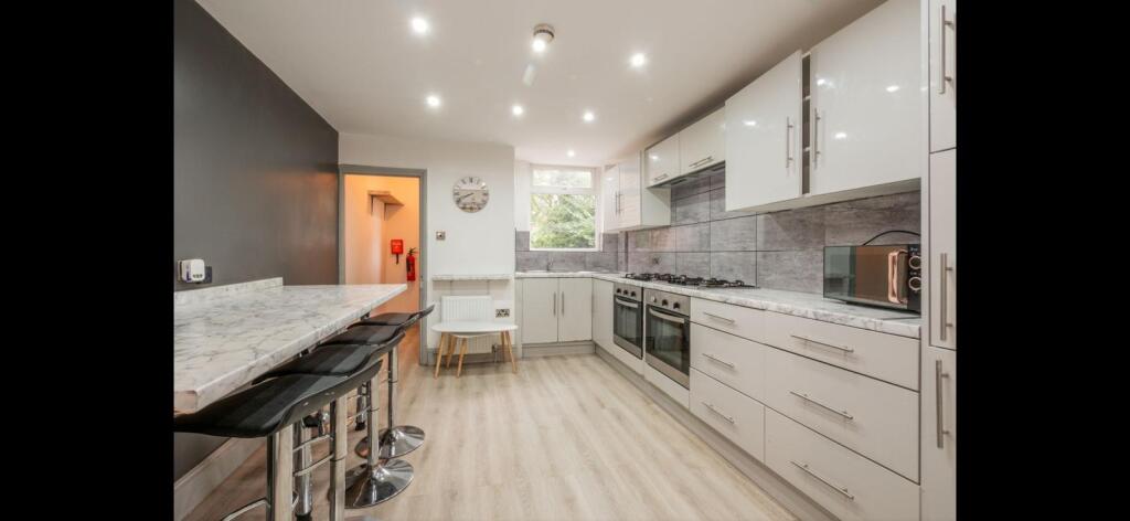 Bright modern galley kitchen with glossy white ...