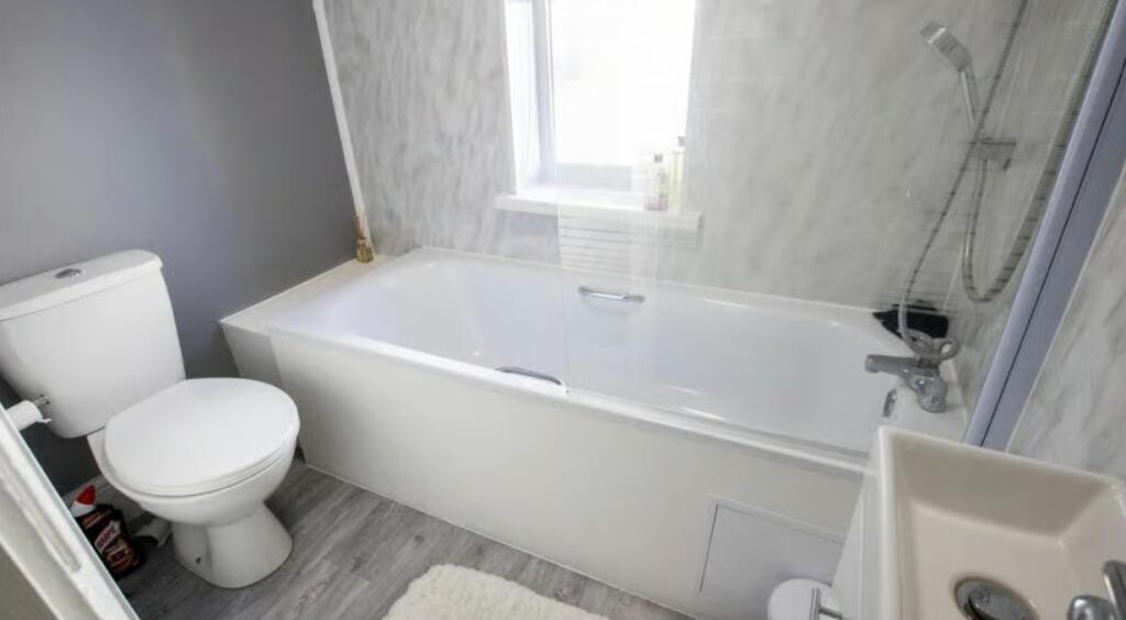 Bright and clean bathroom suite featuring a mod...