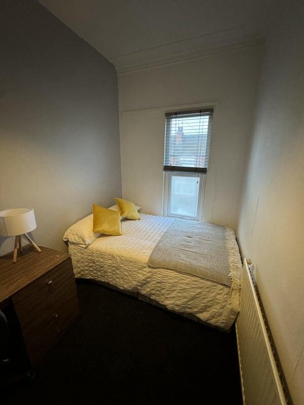Cozy single bedroom featuring a neatly made bed...