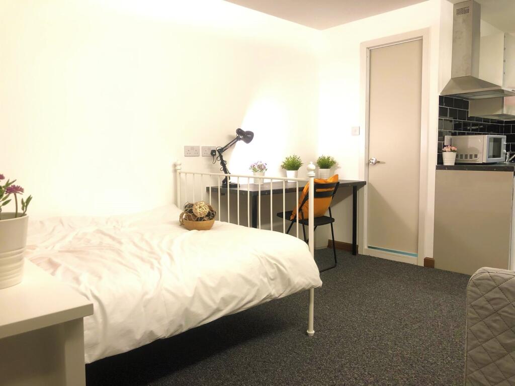 A cozy single bedroom featuring a neatly made w...