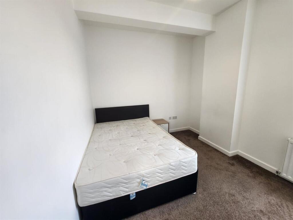 A clean and bright bedroom featuring a bed fram...